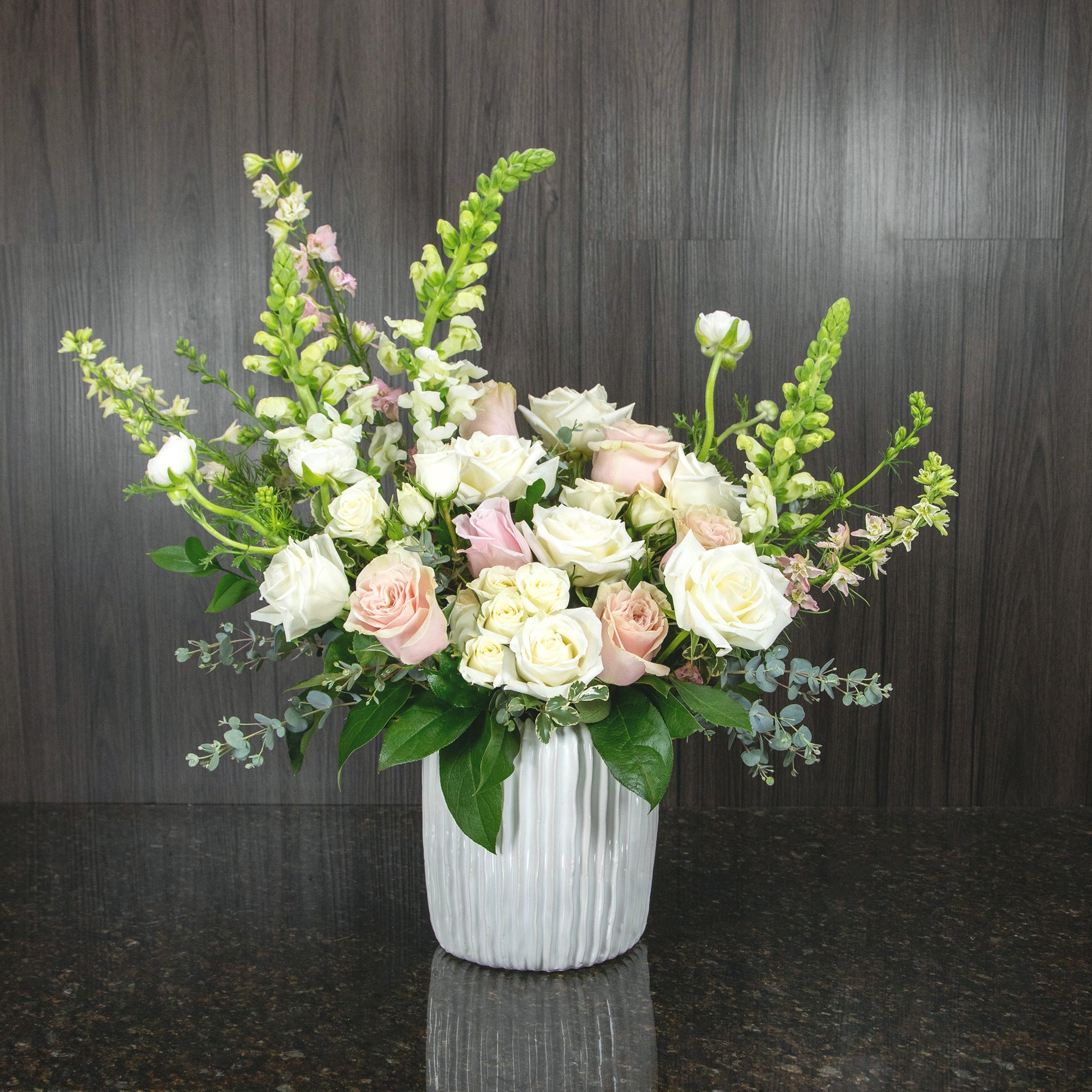 a large flower arrangement of white and pink flowers in a large textured ceramic pot