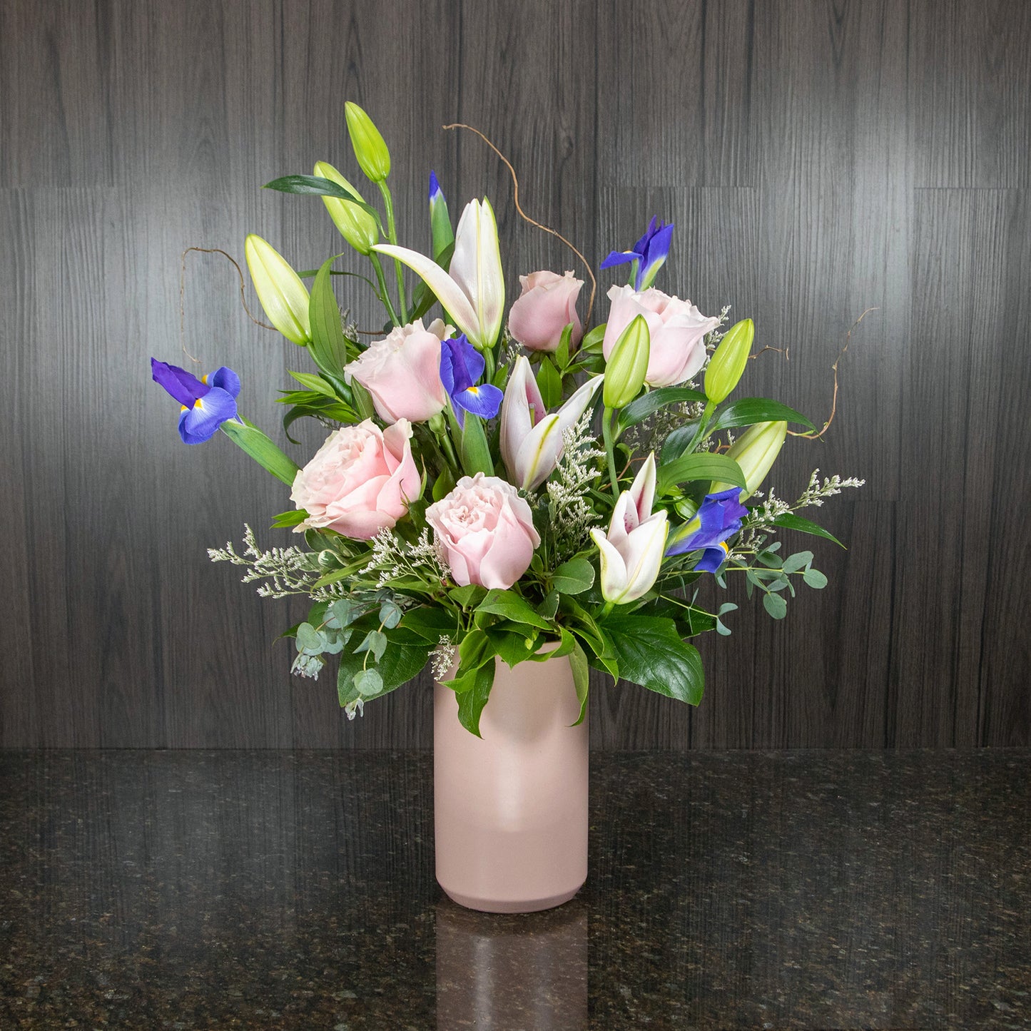 a flower arrangement in pinks, whites, and purples in a tall pink ceramic vase