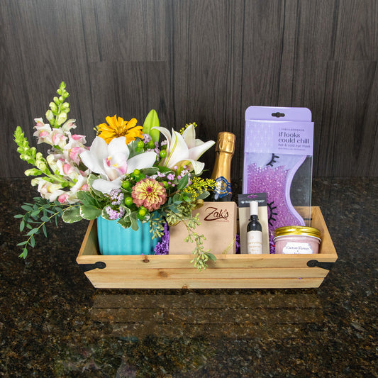 a narrow wooden basket filled with gift items and a small flower arrangement